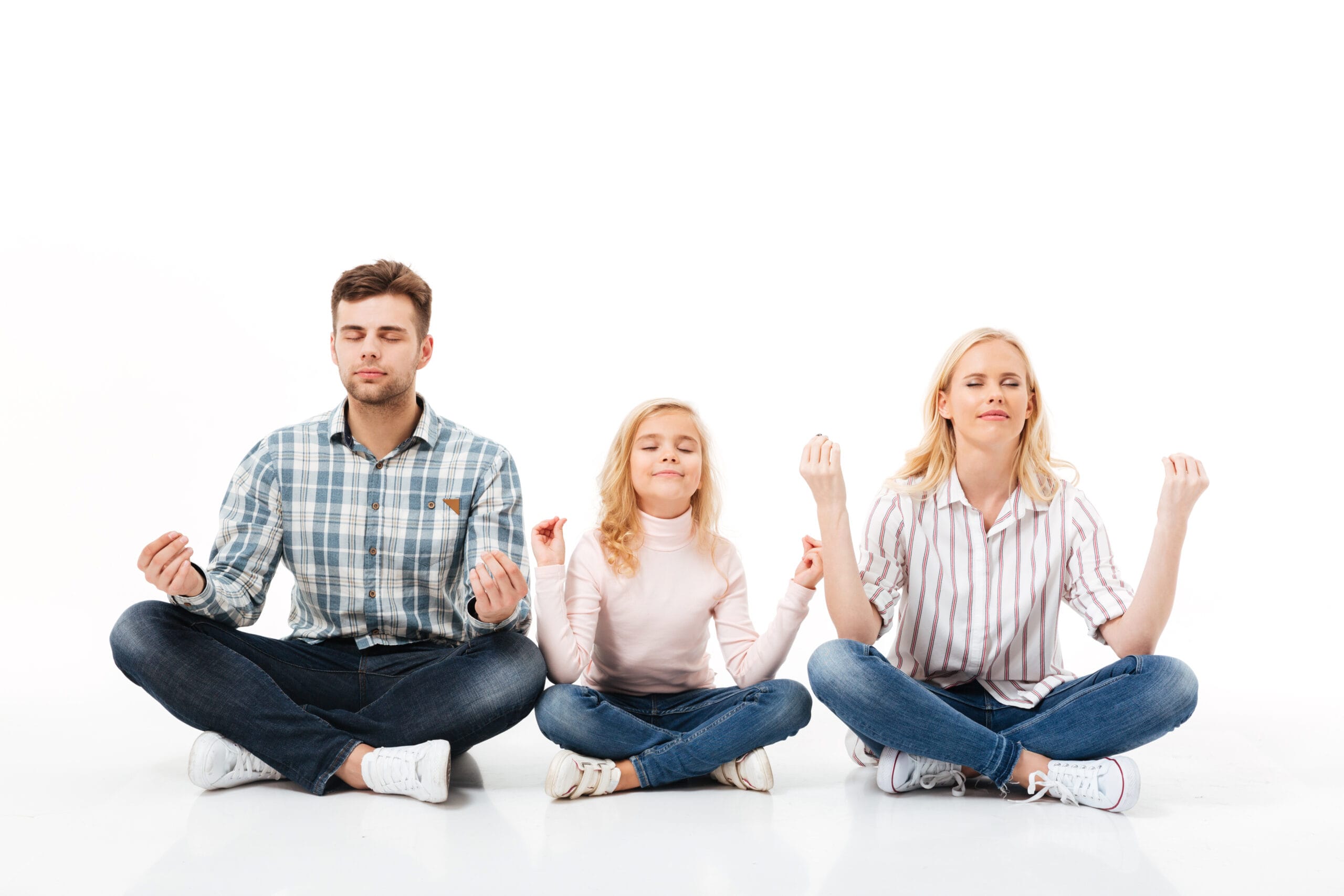 Family meditating together peacefully on the floor.