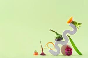 Assorted vegetables on abstract sculpture, green background.