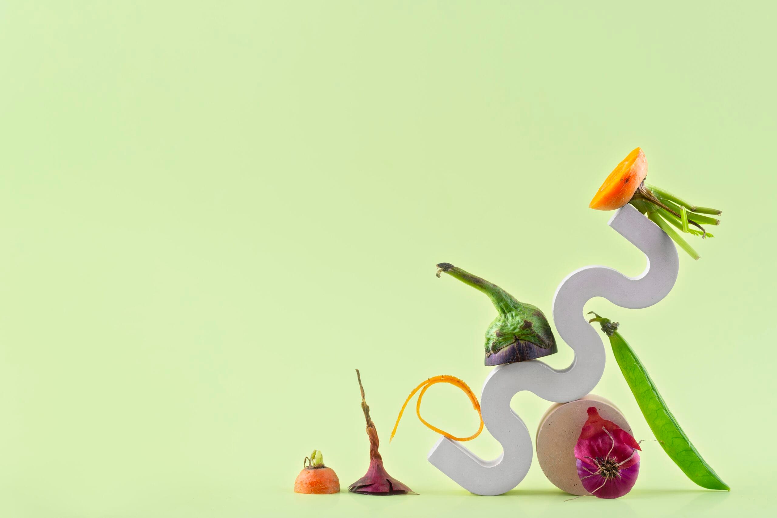 Assorted vegetables on abstract sculpture, green background.
