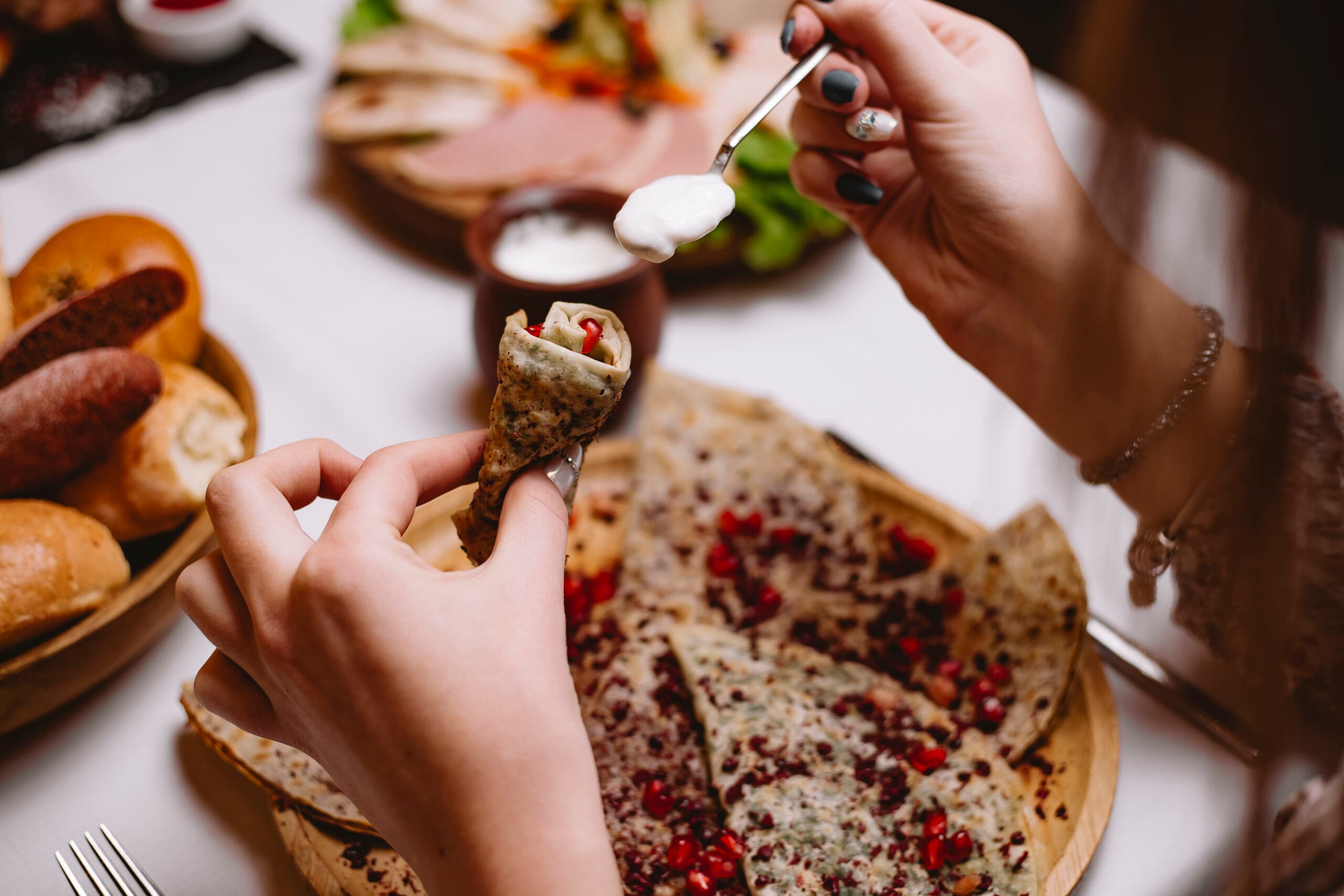 Person adding topping to stuffed flatbread at table
