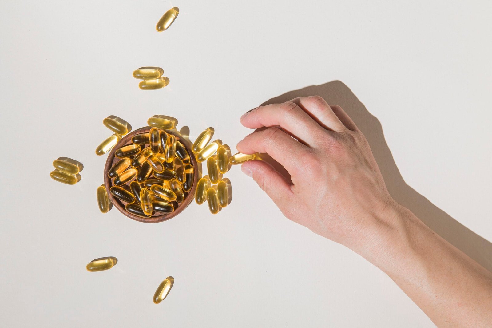 Hand picking omega-3 capsules from bowl