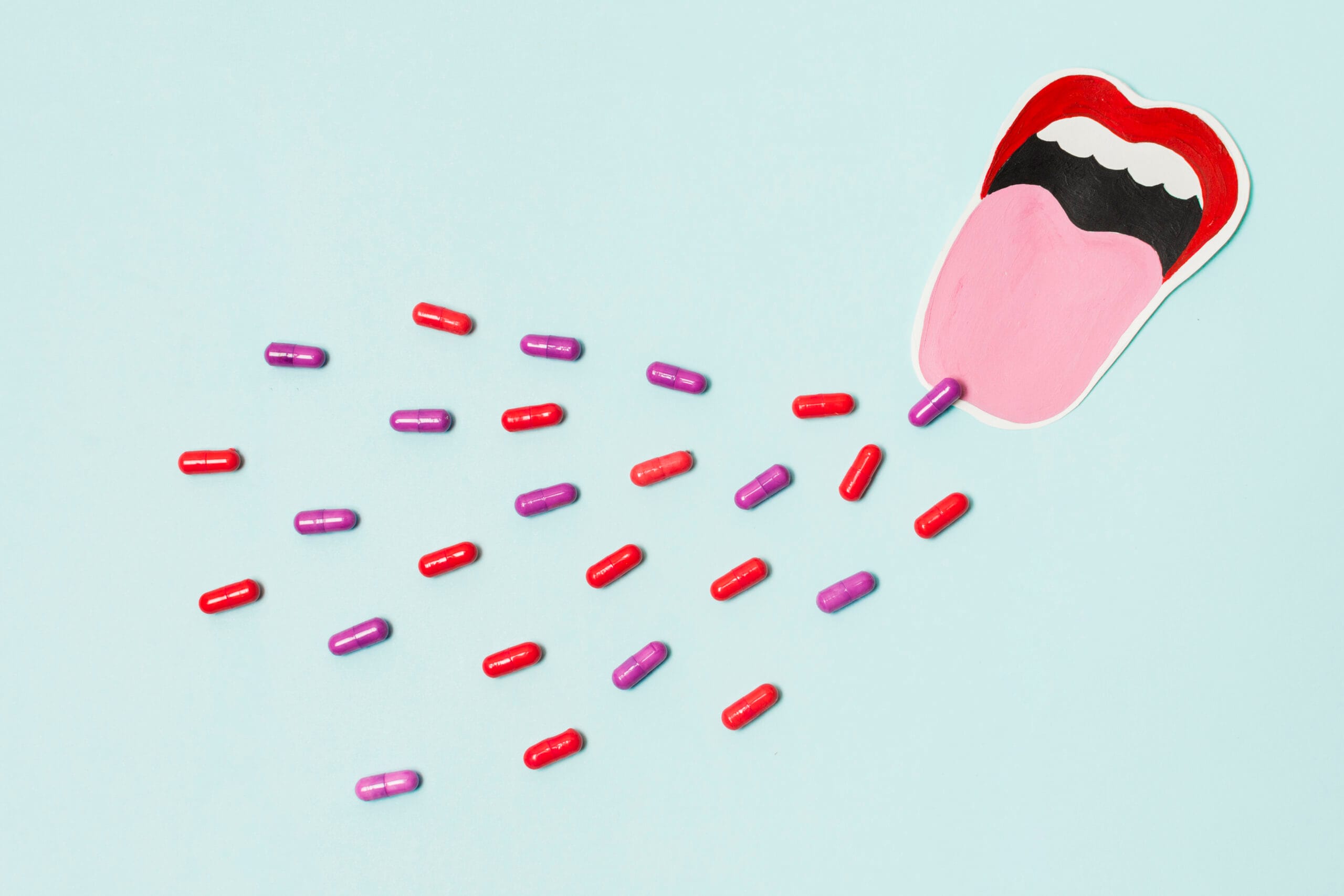 Colorful capsules spilling from a mouth illustration.