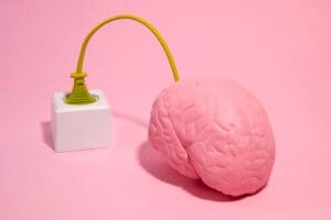 Pink brain connected to gold Eiffel-tower plug.
