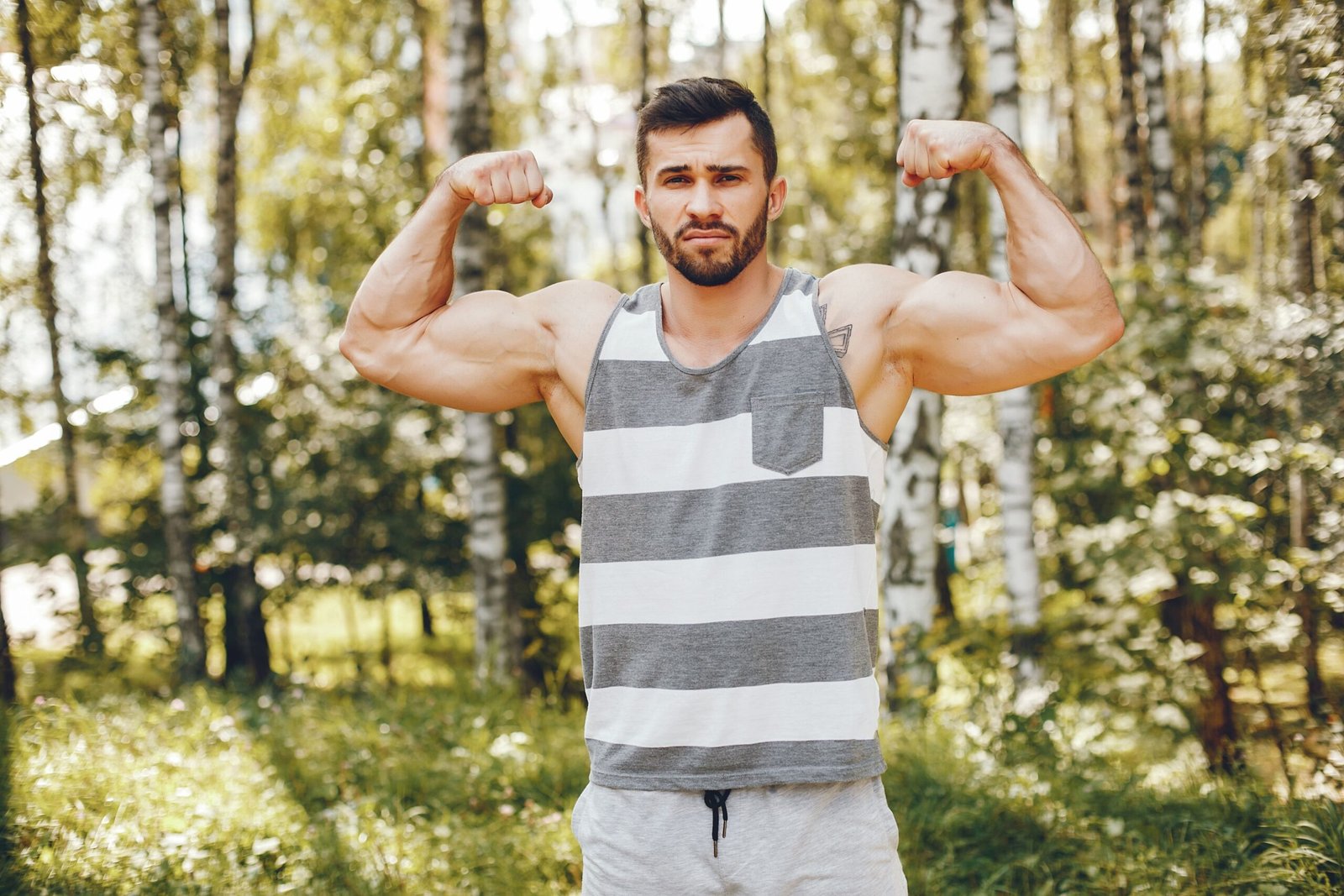 Man flexing muscles in a forest