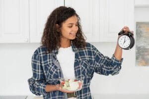 Woman holding salad and clock in kitchen